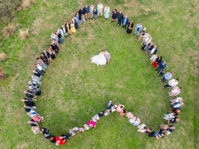 Les invités d'un mariage forment un cœur autour des mariés, vus du ciel